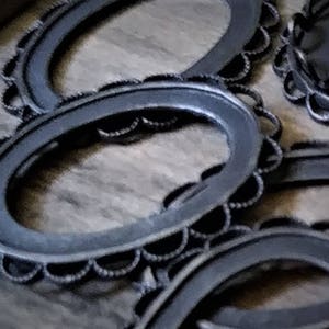 May include: A set of four black metal oval-shaped picture frames with scalloped edges.