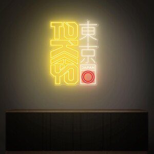 May include: Neon sign with the word "TOKYO" in yellow and Japanese characters in white. The sign includes a red circle with the word "JAPAN" in a white rectangle. The sign is mounted on a dark wall.