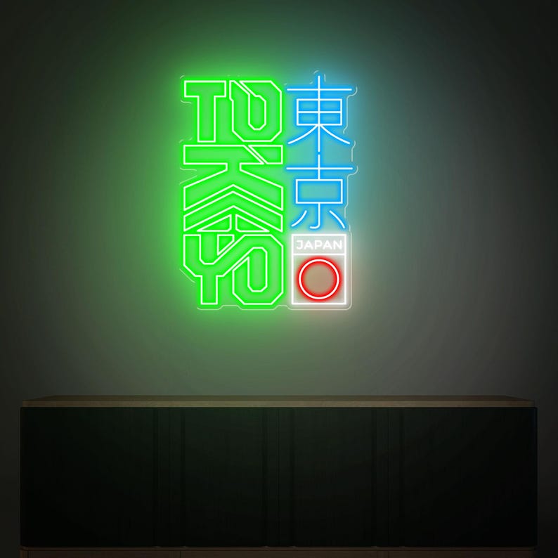 May include: Neon sign with the word "TOKYO" in green and blue, with Japanese characters. The sign includes a white rectangle with the word "JAPAN" and a red circle. The sign is mounted on a dark wall above a dark cabinet.