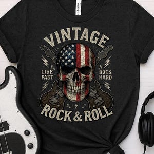 Peut inclure: T-shirt noir avec un motif de cr&acirc;ne orn&eacute; du drapeau am&eacute;ricain, de guitares et les mots "VINTAGE ROCK & ROLL". Le t-shirt porte &eacute;galement les phrases "LIVE FAST" et "ROCK HARD". Une guitare basse et un casque sont dans l'image.