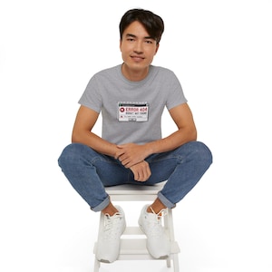 May include: A heather grey short-sleeve t-shirt featuring a graphic print of a computer error window. The graphic displays the text ERROR 404 BUDGET NOT FOUND in red and black lettering, along with a warning icon and a small button labelled OK.
