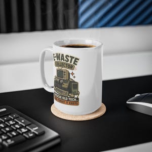 May include: A white ceramic mug featuring a graphic illustration of vintage electronics including a computer, keyboard, and handheld console. The text reads E-WASTE COLLECTOR and I RESCUE OLD TECH... THEN FORGET IT EXISTS in black and orange lettering.