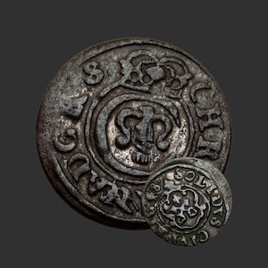 Puede incluir: Dos monedas antiguas de plata con diseños e inscripciones intrincados. La moneda más grande muestra un emblema central rodeado de texto y patrones ornamentados. La moneda más pequeña, también de plata, presenta un diseño similar. Ambas monedas tienen una apariencia desgastada.