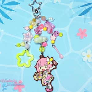 May include: A whimsical keychain featuring a pink anime-style character charm, surrounded by star, flower, and heart-shaped beads in pastel colors. The keychain includes a star-shaped clasp and a variety of decorative elements.