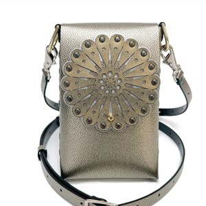 May include: A silver metallic crossbody bag with a large, decorative, gold-toned flower design. The flower has a white center and is accented with silver studs.