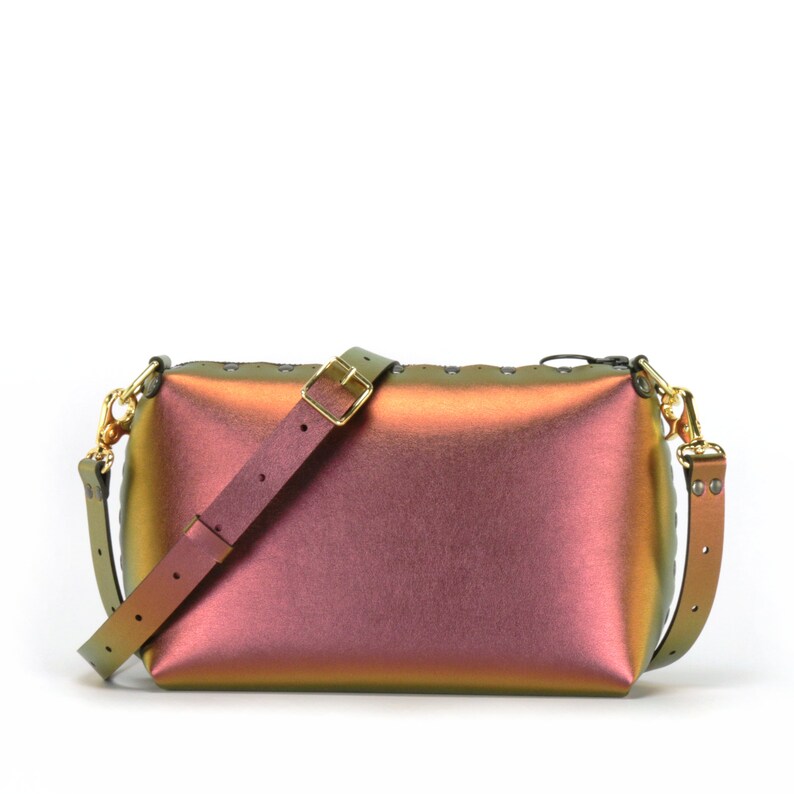 May include: A small iridescent green, purple, and pink crossbody bag with a gold buckle and a black strap.