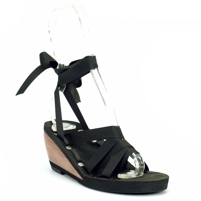 Mid wedge slide ribbon sandal.  Photo highlights the sandals footbed that is composed of 1/4 inch foam pad and vegan suede.  Ribbon loops are in a slide style with four hand riveted side loops.  Shown with black ribbon tied from front to back.
