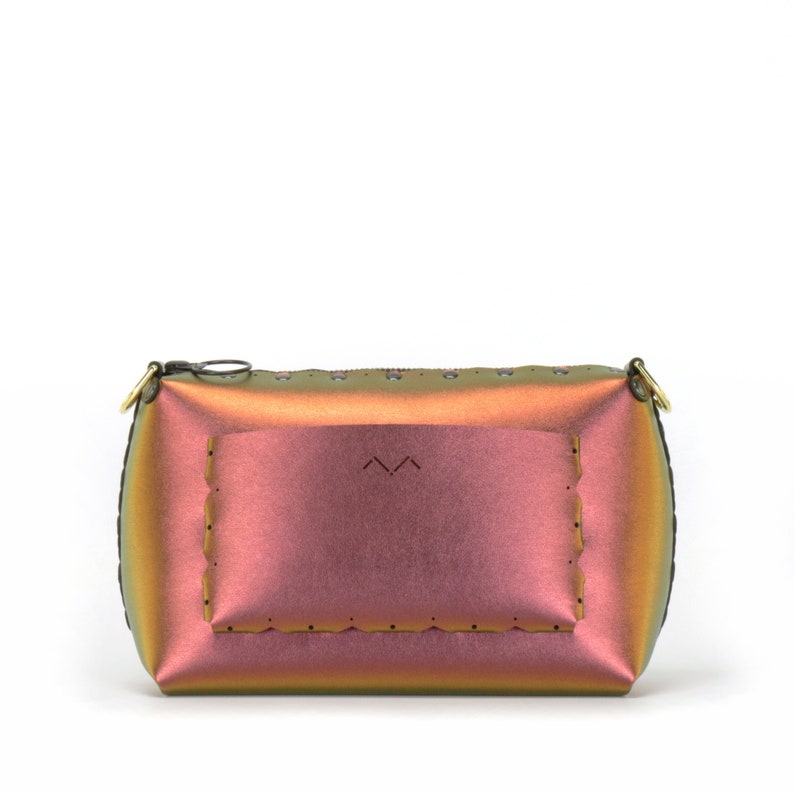 May include: A small iridescent handbag with a zip closure and a gold accent. The bag has a unique design with a scalloped edge and a small pocket on the front.