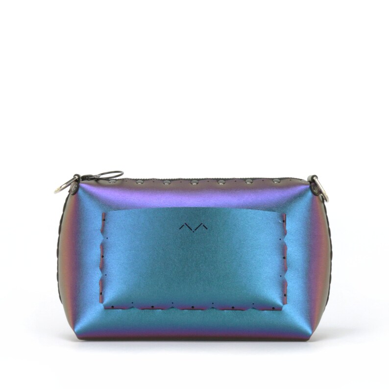 May include: Iridescent clutch purse with a zipper closure and a small silver-tone ring. The bag has a rectangular shape with a stitched border and a rectangular design on the front. The color shifts between blue, purple, and green.