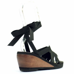 3/4 rear view of mid wedge ribbon sandals.  Photo highlight the ergonomically carved walnut wood heel. The wood wedge is topped with 1/4" foam pad and luxury vegan suede.  Sandal is laced with 5/8" black ribbon that ties around the ankle.