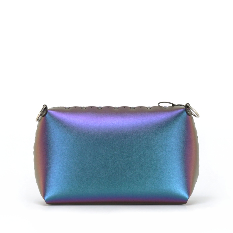 May include: Iridescent rectangular clutch with a zipper closure and small metal rings on the corners. The bag transitions from purple to teal and blue. The top edge has small, evenly spaced holes.