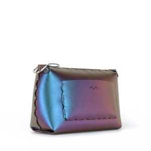 May include: Iridescent clutch with a scalloped edge and a small pocket. The clutch transitions from blue to purple, with a silver-tone ring attached to the zipper. The pocket has a stitched border and a small design.