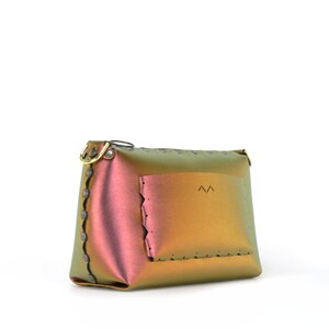 May include: A small iridescent green and pink leather bag with a flap pocket and a gold metal clasp. The bag has a scalloped edge and a small logo on the front.