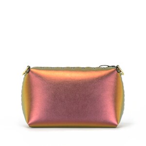 May include: A small, iridescent, rectangular handbag with a gold zipper and gold hardware. The bag is made of a smooth, shiny material and has a slight sheen.