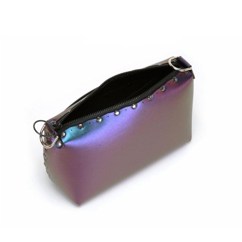 May include: Iridescent purple and blue zippered pouch with silver-tone rivets and a black interior. The open pouch has a silver ring attached to the zipper pull. The pouch is on a white background.