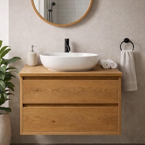 May include: A modern bathroom vanity with a white oval sink and black faucet. The vanity is made of light-colored wood with two drawers. A round wooden-framed mirror hangs above the sink. A towel ring and a soap dispenser are also visible.
