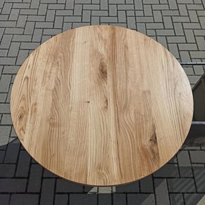 以下が含まれることがあります： 自然な木目仕上げの丸い木製テーブルトップ。テーブルトップは明るい茶色の木でできており、表面は滑らかです。