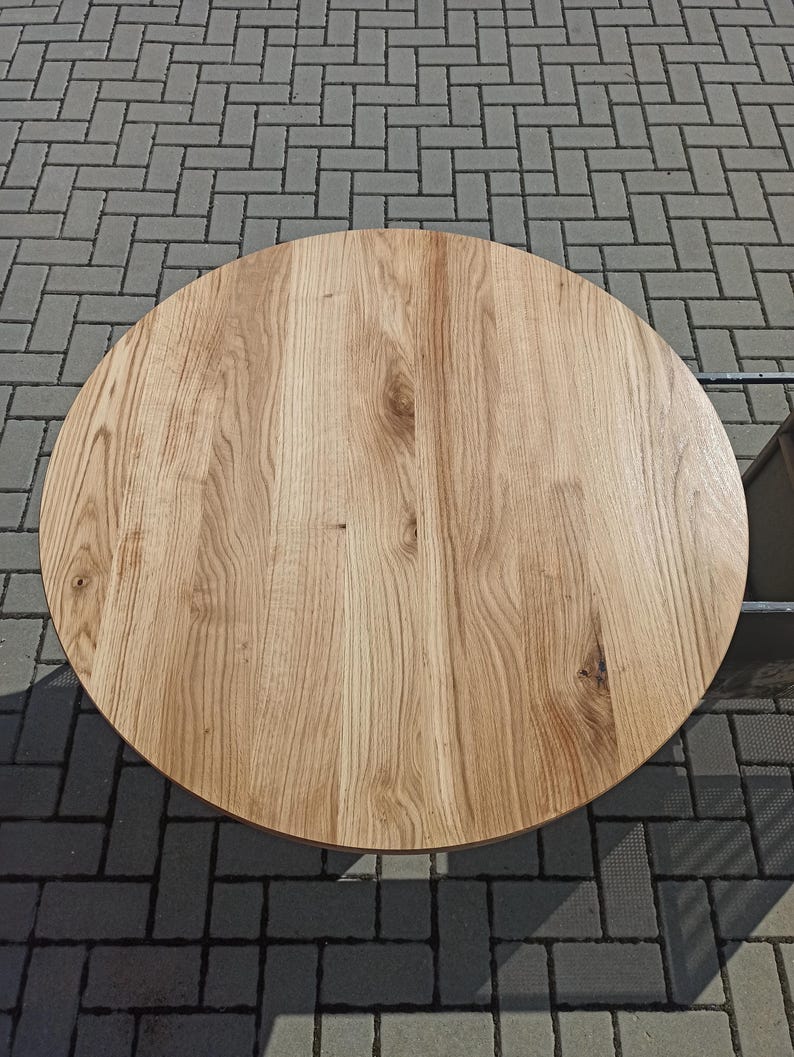 以下が含まれることがあります： 自然な木目仕上げの丸い木製テーブルトップ。テーブルトップは明るい茶色の木でできており、表面は滑らかです。