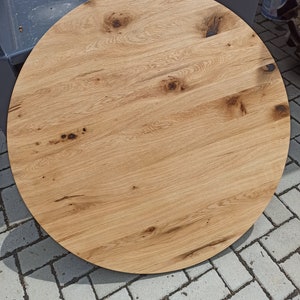 以下が含まれることがあります： 自然な木目仕上げの丸い木製テーブルトップ。テーブルトップは薄い茶色で、濃い茶色の節と木目が特徴です。