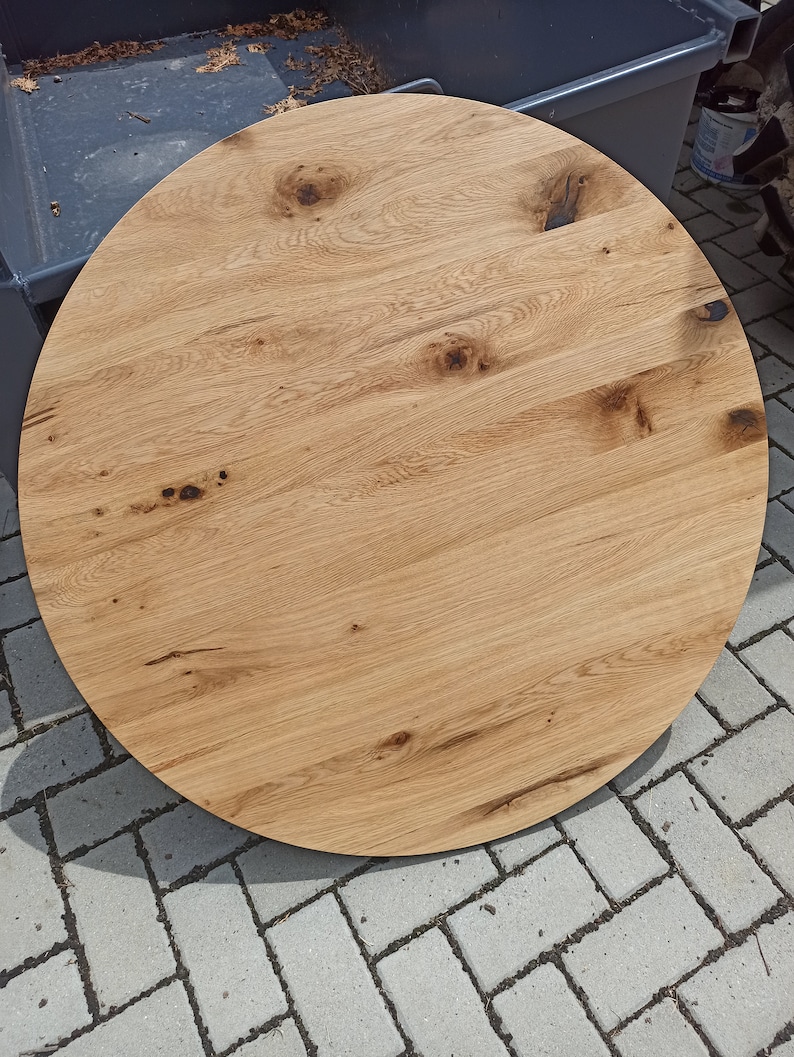 以下が含まれることがあります： 自然な木目仕上げの丸い木製テーブルトップ。テーブルトップは薄い茶色で、濃い茶色の節と木目が特徴です。