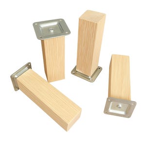 May include: Four unfinished wooden furniture legs with metal mounting plates. The legs are rectangular and light-colored, with visible wood grain. The metal plates are square and silver.