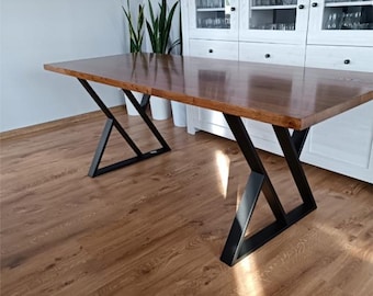 Könnte beinhalten: Ein Esstisch aus Holz mit einer braunen Tischplatte und schwarzen Metallbeinen. Die Beine haben eine geometrische, dreieckige Form.