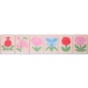 May include: Eight pink mahjong tiles with different flower designs. The flowers are in shades of pink, red, blue, and green.