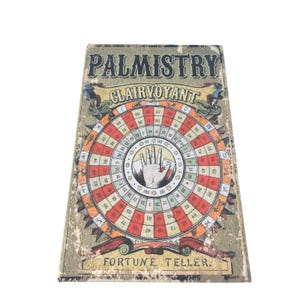 May include: A vintage palmistry board with the text "Palmistry Clairvoyant Fortune Teller". The board has a central circular design with a hand illustration and numbers, in shades of red, orange, and green, with a distressed finish.