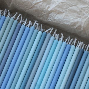 Peut inclure: Un assortiment de bougies coniques bleues de diff&eacute;rentes nuances, du bleu clair au bleu fonc&eacute;, dispos&eacute;es dans une bo&icirc;te. Chaque bougie a une m&egrave;che blanche. Ces bougies sont un article d&eacute;coratif, pour la d&eacute;coration int&eacute;rieure ou les &eacute;v&eacute;nements.