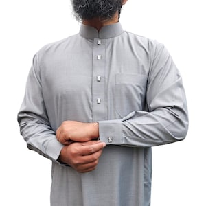 Puede incluir: Una camisa gris de manga larga con cuello alto y cierre de botones. La camisa tiene un bolsillo en el lado izquierdo y un sutil patrón texturizado.