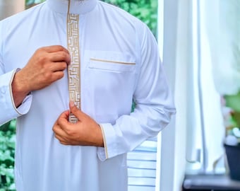 May include: A white long-sleeved shirt with a gold geometric pattern down the front. The shirt has a high collar and is buttoned up.