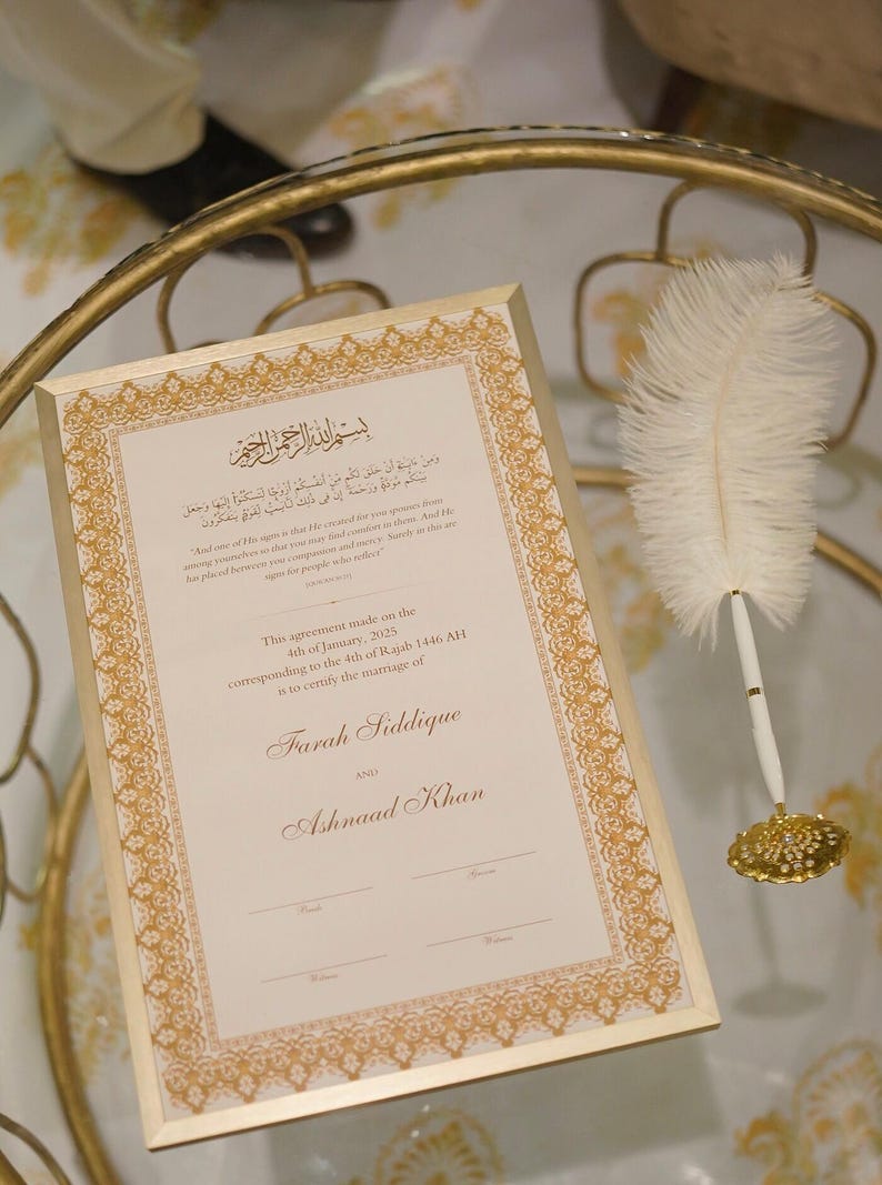 Puede incluir: Un certificado enmarcado en oro con una pluma de pluma blanca y un tintero. El certificado es para el matrimonio de Farah Siddique y Ashnaad Khan. La fecha del matrimonio es el 4 de enero de 2025, correspondiente al 4 de Rajab 1446 AH.