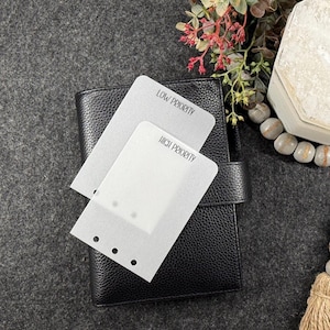 May include: Two translucent, frosted plastic planner dividers with rounded corners. One divider is labeled LOW PRIORITY and the other is labeled HIGH PRIORITY in black text. Each divider features a vertical row of three circular punched holes.