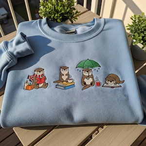 Fall Otter Embroidered Sweatshirt, Otter Lovers Crewneck, Sea Otter T-Shirt, Reading Gift For Women, Autumn Animal Hoodie, Cozy Bookish Tee