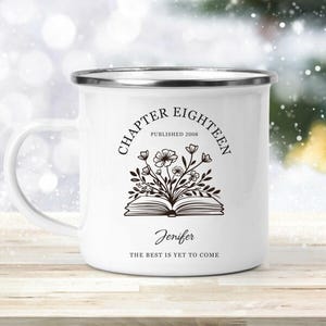 May include: White enamel mug with a silver rim and handle. The mug features the text "CHAPTER EIGHTEEN PUBLISHED 2008" in a circular design, with a floral illustration over an open book. The name "Jenifer" and the phrase "THE BEST IS YET TO COME" are also printed on the mug.