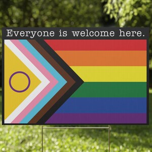 May include: A yard sign with a rainbow pride flag and the text "Everyone is welcome here."