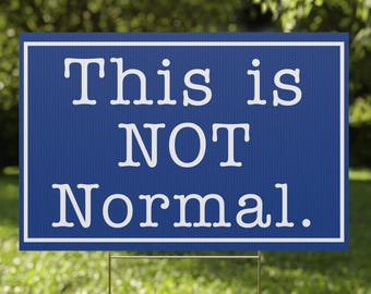 May include: A blue yard sign with white text that reads "This is NOT Normal."
