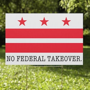 May include: A rectangular sign with a white background, red stripes, and three red stars. The text "NO FEDERAL TAKEOVER" is printed in black at the bottom. The sign is mounted on a metal stake and placed in grass.