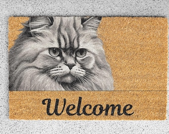 May include: A brown coir doormat with a black and white illustration of a cat's face and the word "Welcome" in black text.