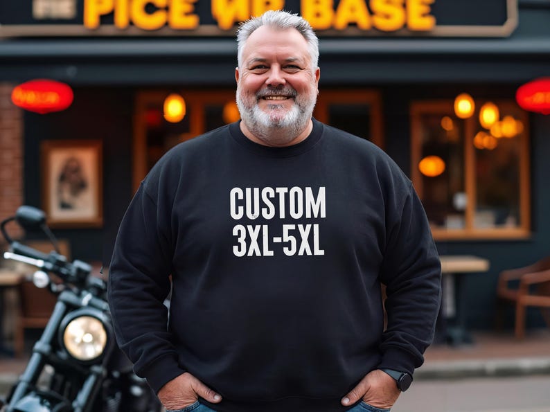 May include: A black sweatshirt with the text "CUSTOM 3XL-5XL" in white. The sweatshirt is worn by a person. The background includes a restaurant and a motorcycle.