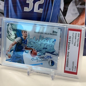 May include: A basketball card featuring Cooper Flagg of the Dallas Mavericks, encased for protection. The card displays the text "CLUTCHCITY Prospects" and the Topps logo. It is graded GEM MINT 10.
