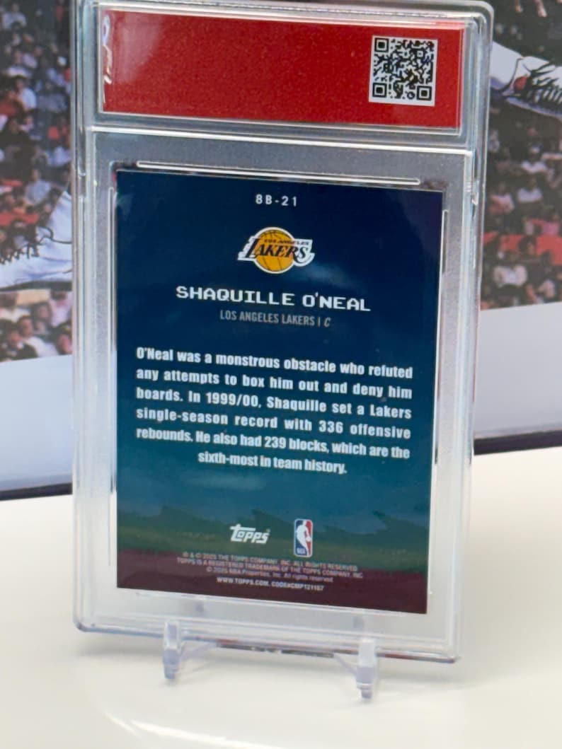 May include: A basketball card featuring Shaquille O'Neal of the Lakers, displayed in a protective case. The card's reverse side details O'Neal's accomplishments, including a record of 336 offensive rebounds in the 1999/00 season.