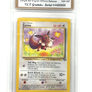 May include: A graded Pokémon card featuring Eevee from the 1999 Jungle Set. The card is encased in a protective holder and displays the text "Eevee" along with its HP and attack details. The card is graded NM-MT.