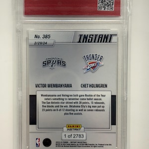 Op de afbeelding: Een basketbal trading card in een heldere beschermhoes. De kaart toont de logo's van de San Antonio Spurs en Oklahoma City Thunder, en de namen Victor Wembanyama en Chet Holmgren. Tekst beschrijft hun Rookie of the Year prestaties.