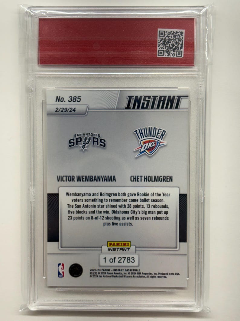 Op de afbeelding: Een basketbal trading card in een heldere beschermhoes. De kaart toont de logo's van de San Antonio Spurs en Oklahoma City Thunder, en de namen Victor Wembanyama en Chet Holmgren. Tekst beschrijft hun Rookie of the Year prestaties.