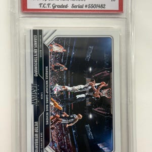 May include: A basketball trading card featuring Giannis Antetokounmpo and Victor Wembanyama. The card is graded GEM MINT 10 by T.C.T. and is part of the 2023-24 Panini Instant NBA series. The card's title is "Match Up Earns Rave Reviews."