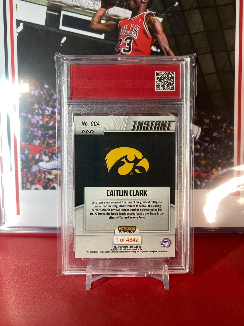 May include: A trading card featuring Caitlin Clark, a basketball player for the University of Iowa. The card is silver with a black background and features a photo of Clark in her Iowa uniform. The card is numbered 2/2/25 and is part of the Instant set. The card also includes a quote from Clark about her return to school after a successful collegiate career.