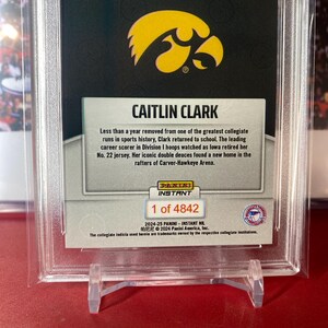 May include: A trading card featuring Caitlin Clark, a basketball player for the University of Iowa. The card is part of the 2024-25 Panini Instant NIL series and is numbered 1 of 4842. The card features a photo of Clark in her Iowa uniform, along with her name and the team's logo. The card also includes a description of Clark's achievements, including her status as the leading career scorer in Division I women's basketball.