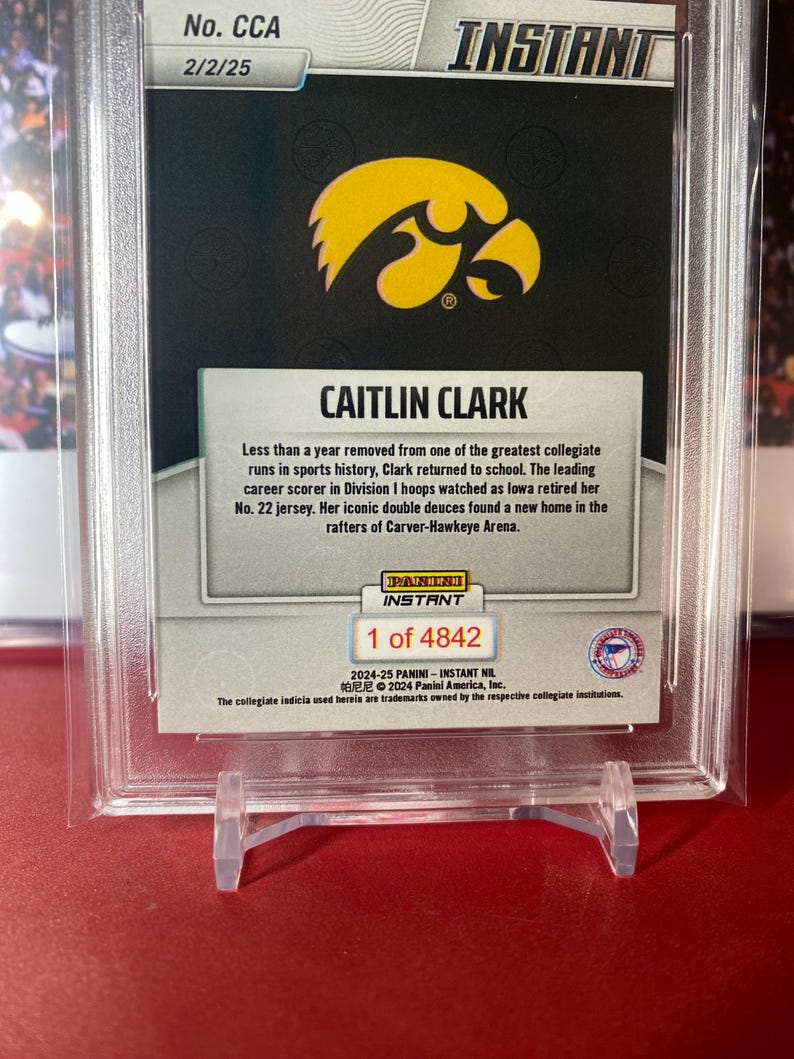 May include: A trading card featuring Caitlin Clark, a basketball player for the University of Iowa. The card is part of the 2024-25 Panini Instant NIL series and is numbered 1 of 4842. The card features a photo of Clark in her Iowa uniform, along with her name and the team's logo. The card also includes a description of Clark's achievements, including her status as the leading career scorer in Division I women's basketball.