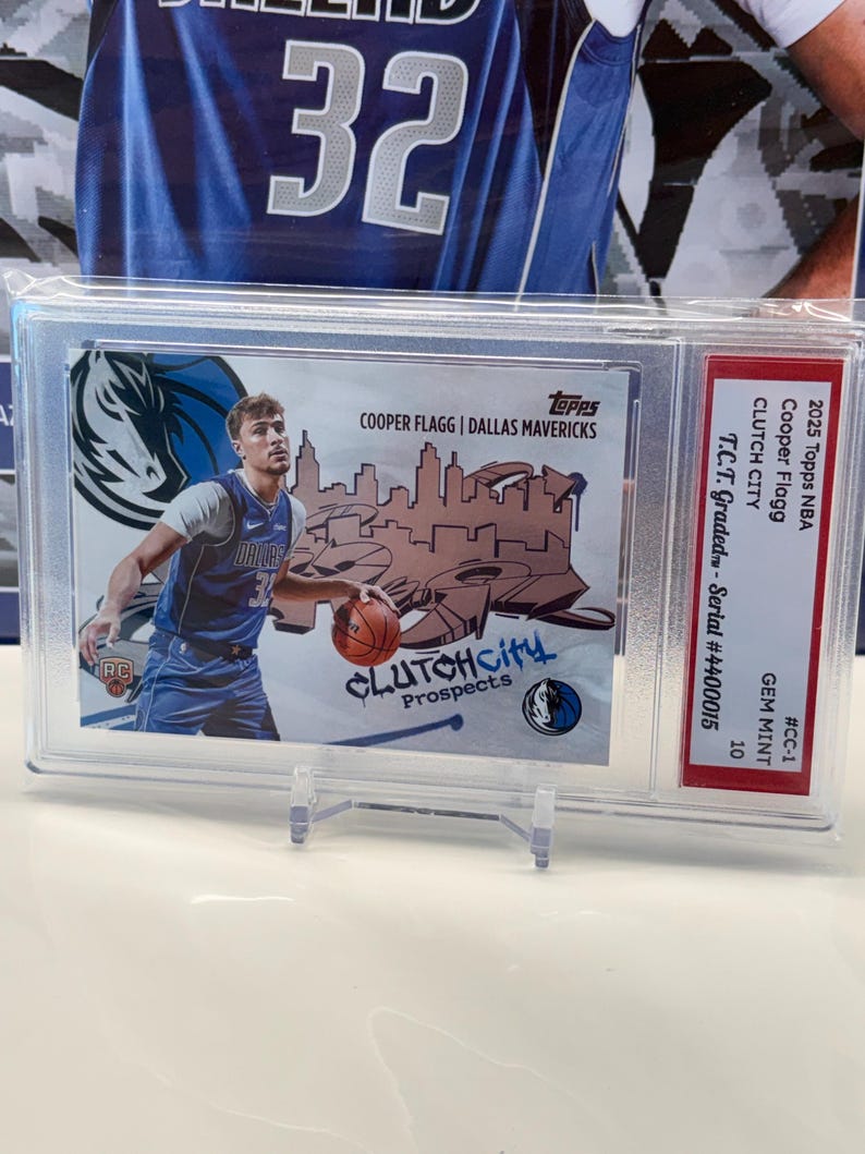 May include: A basketball card featuring Cooper Flagg of the Dallas Mavericks, encased for protection. The card displays the team logo and the text "CLUTCH City Prospects." It is graded and has a serial number.